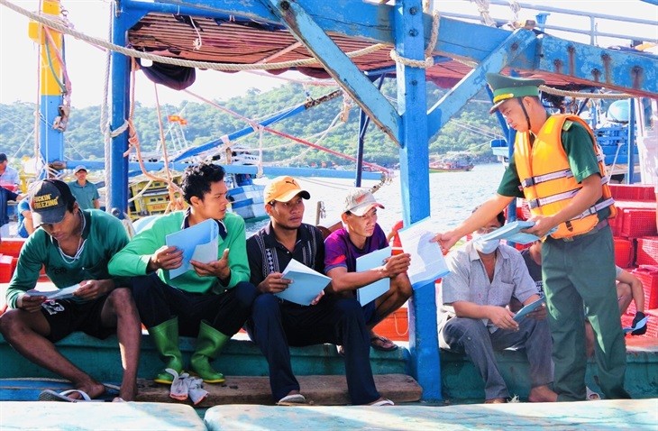 Cán bộ Đồn Biên phòng Thổ Châu tổ chức tuyên truyền pháp luật và phát tài liệu cho ngư dân. Ảnh: Khánh An