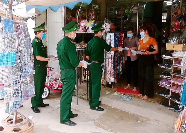 Cán bộ Đồn Biên phòng cửa khẩu quốc tế Bình Hiệp phát tờ rơi tuyên truyền, vận động người dân tham gia đấu tranh, ngăn chặn các hoạt động vi phạm pháp luật trên tuyến biên giới. Ảnh: Minh Luận