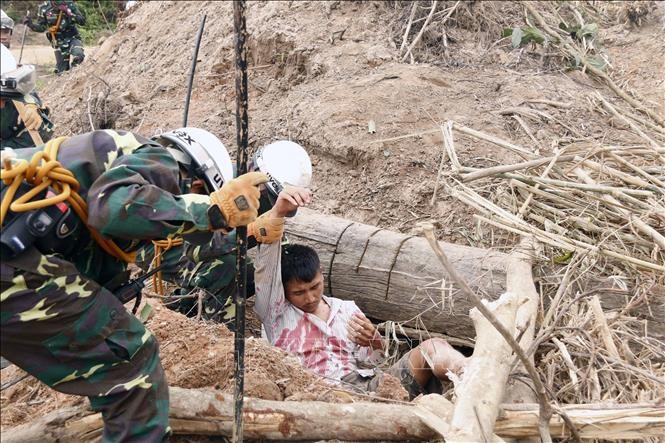 Các chiến sĩ đang đưa một người dân bị cây đè và bị vùi lấp đi cấp cứu trong một tình huống giả định tại diễn tập. (Ảnh: Phạm Kiên/Phóng viên TTXVN tại Lào).