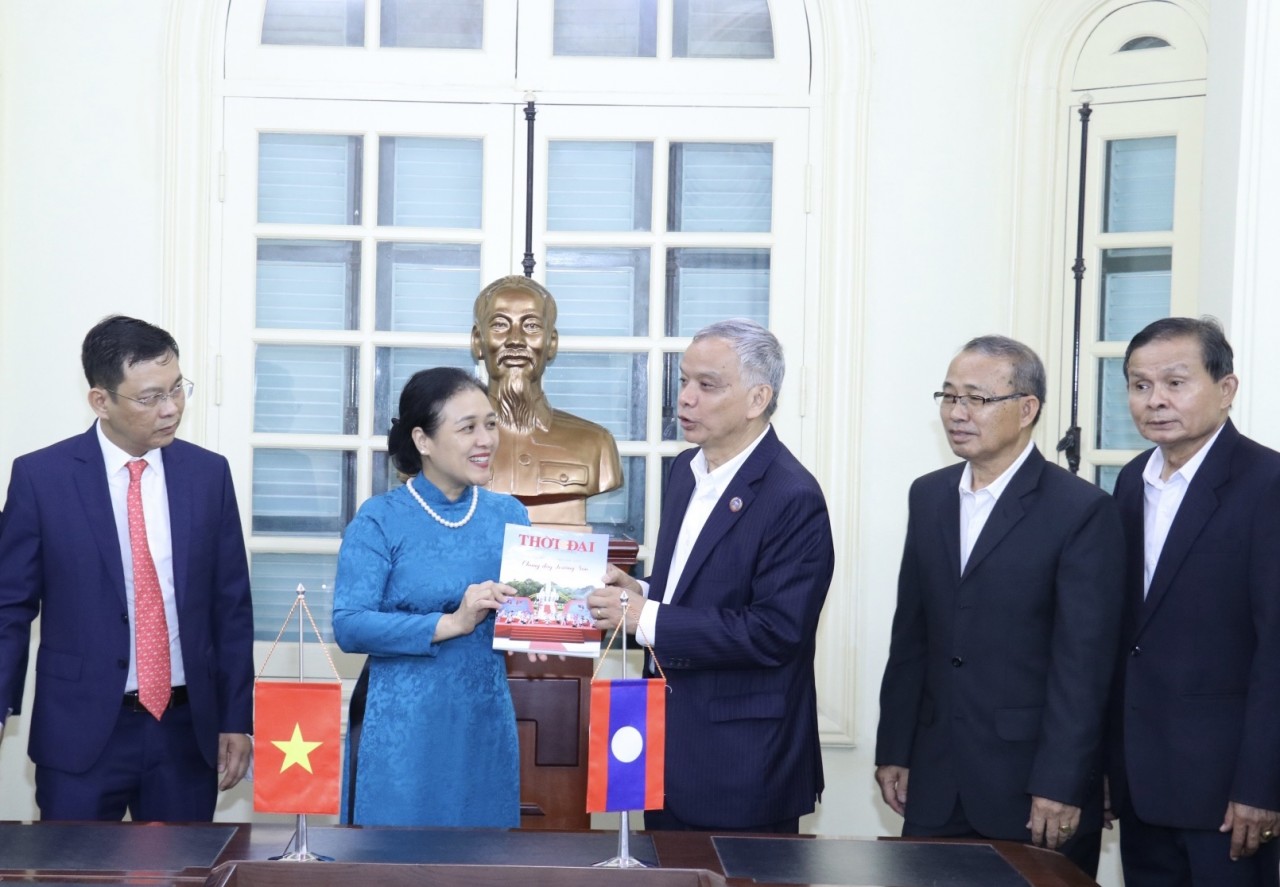 Bà Nguyễn Phương Nga tặng Chủ tịch Ủy ban Hòa bình và Đoàn kết Lào Sommad Pholsena cuốn đặc san “60 năm hữu nghị Việt Nam – Lào: Chung dãy Trường Sơn” của tạp chí Thời Đại (Ảnh: Thu Hà).