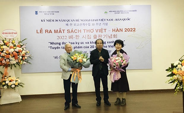 Nhà thơ Nguyễn Quang Thiều tặng hoa cho 2 tác giả Bang young Kang (phải) và Nguyễn Đình Tâm (trái)
