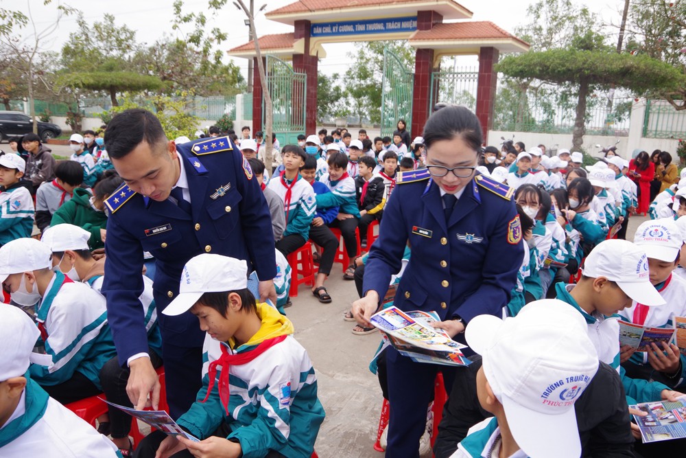 Cán bộ Cảnh sát biển phát tờ rơi tuyên truyền cho học sinh.