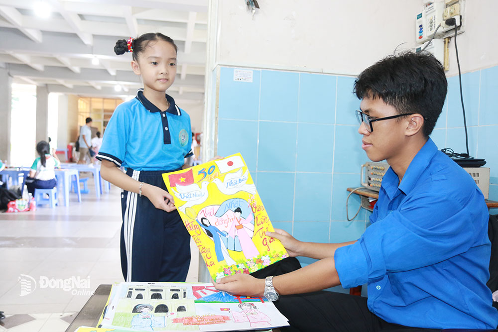 Một học sinh nộp bức tranh vừa hoàn thành cho Ban tổ chức tại hội thi vẽ tranh 50 năm quan hệ hợp tác, hữu nghị Việt Nam - Nhật Bản. Ảnh: S.Thao