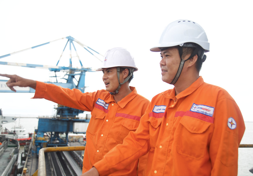 A group of men wearing white helmets and orange jumpsuitsDescription automatically generated