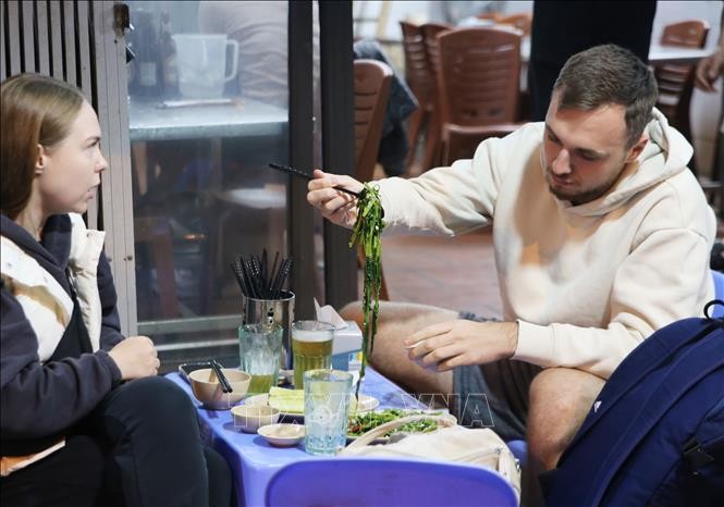 Du khách thưởng thức món rau muống xào, món ăn bình dị và rất phổ biến của Việt Nam.