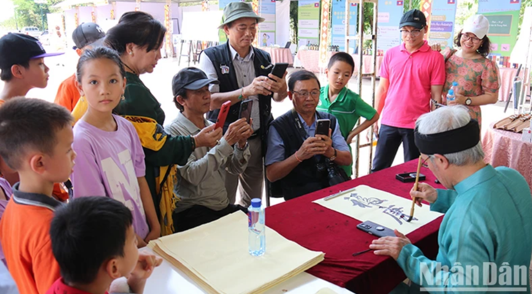Các em học sinh và người dân hai nước thích thú thưởng thức nghệ thuật thư pháp tại sự kiện. (Ảnh: Hải Tiến)