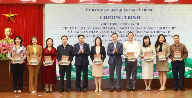 Bí thư Quận ủy Hai Bà Trưng Nguyễn Văn Nam và Phó Giám đốc Sở VH&TT Hà Nội Phạm Xuân Tài trao tặng cuốn sách cho đại diện các phòng, ban, ngành quận (Ảnh: T.L).