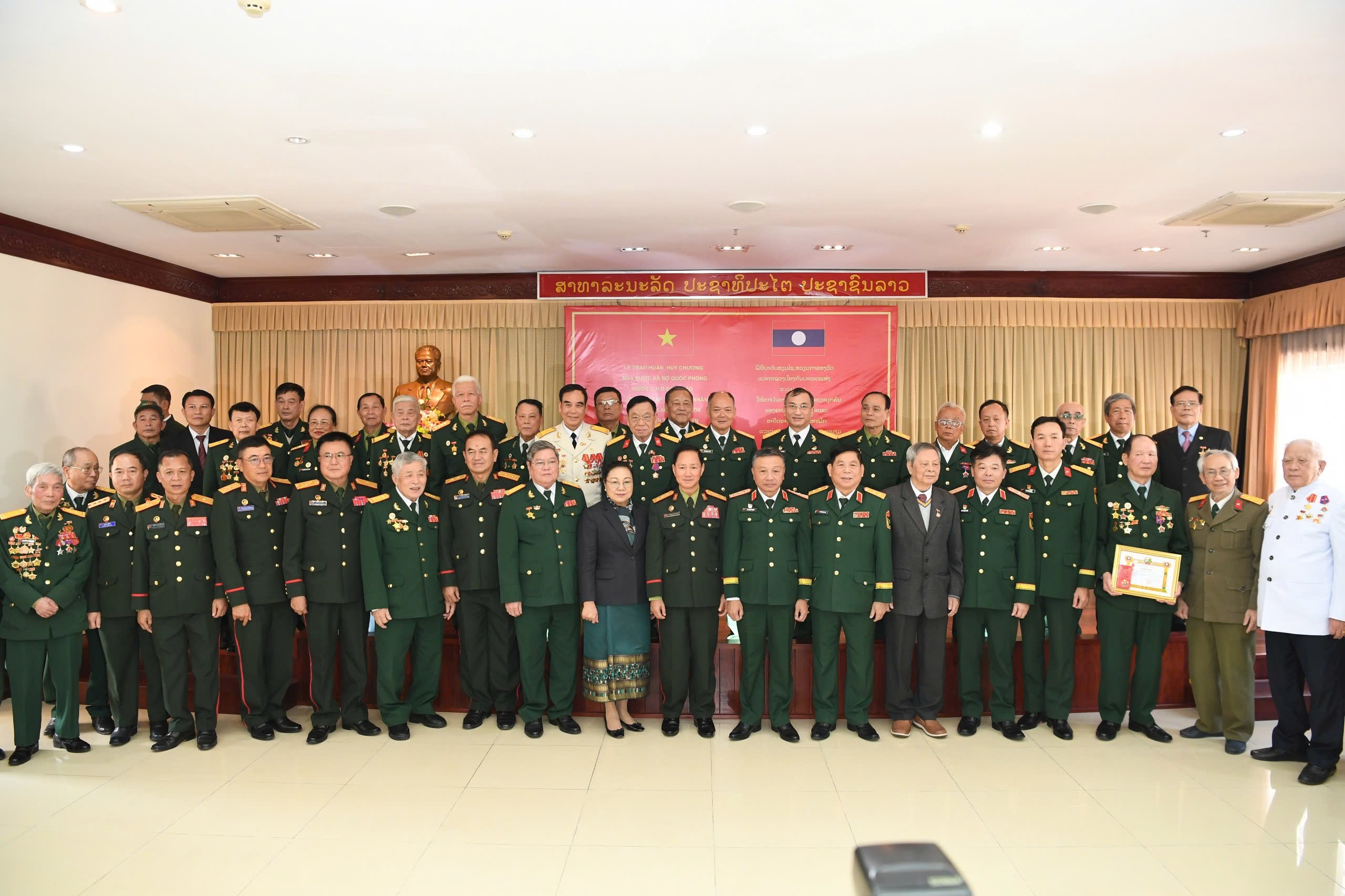 Bộ trưởng Bộ Quốc phòng Lào và các đại biểu chụp ảnh lưu niệm cùng các cựu quân tình nguyện và chuyên gia quân sự Việt Nam giúp cách mạng Lào tại buổi lễ. 