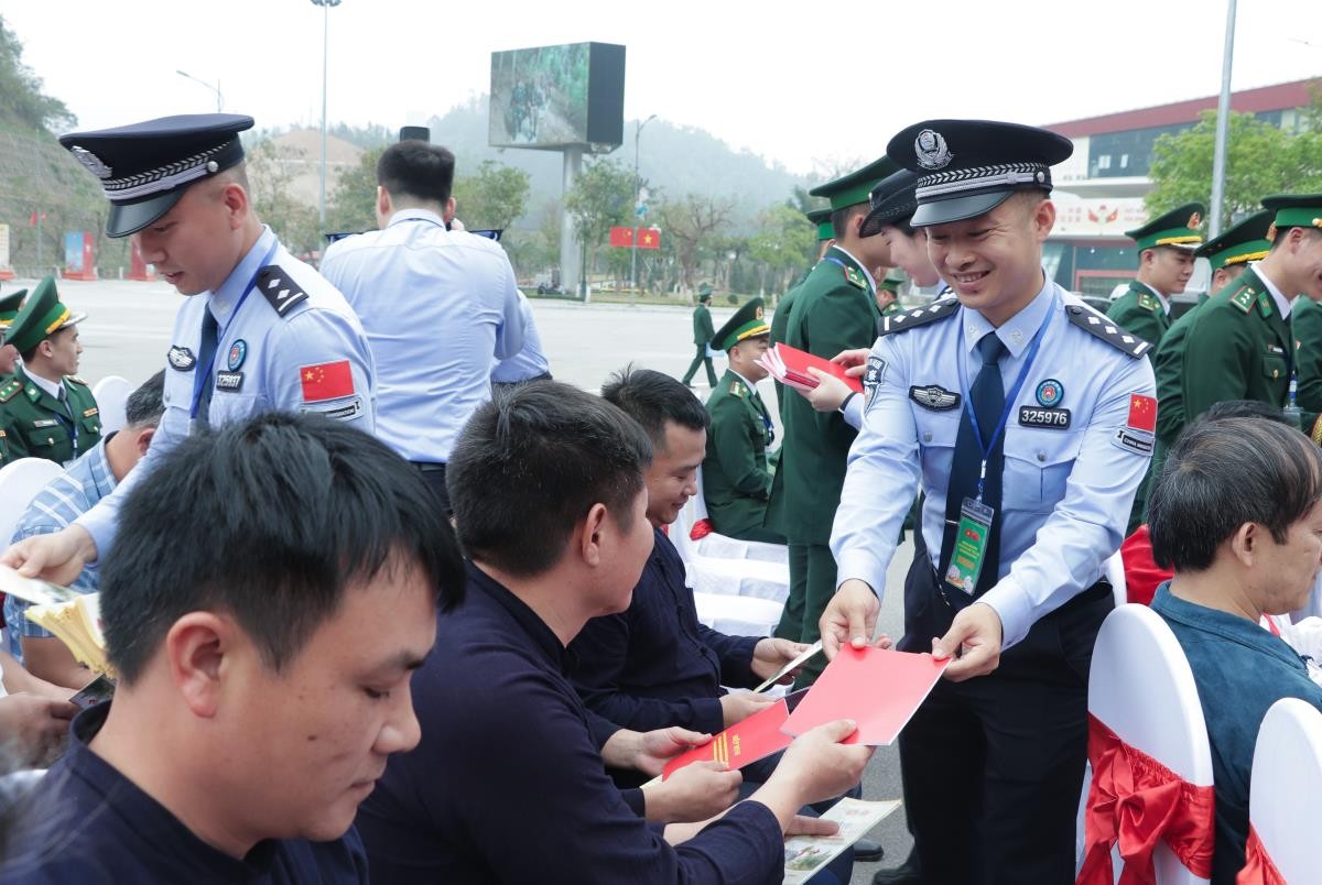 Cán bộ trẻ Tổng trạm Kiểm tra Biên phòng xuất nhập cảnh Quảng Tây (Trung Quốc) phát tờ rơi tuyên truyền pháp luật cho cư dân biên giới. (Ảnh: Báo Biên phòng)