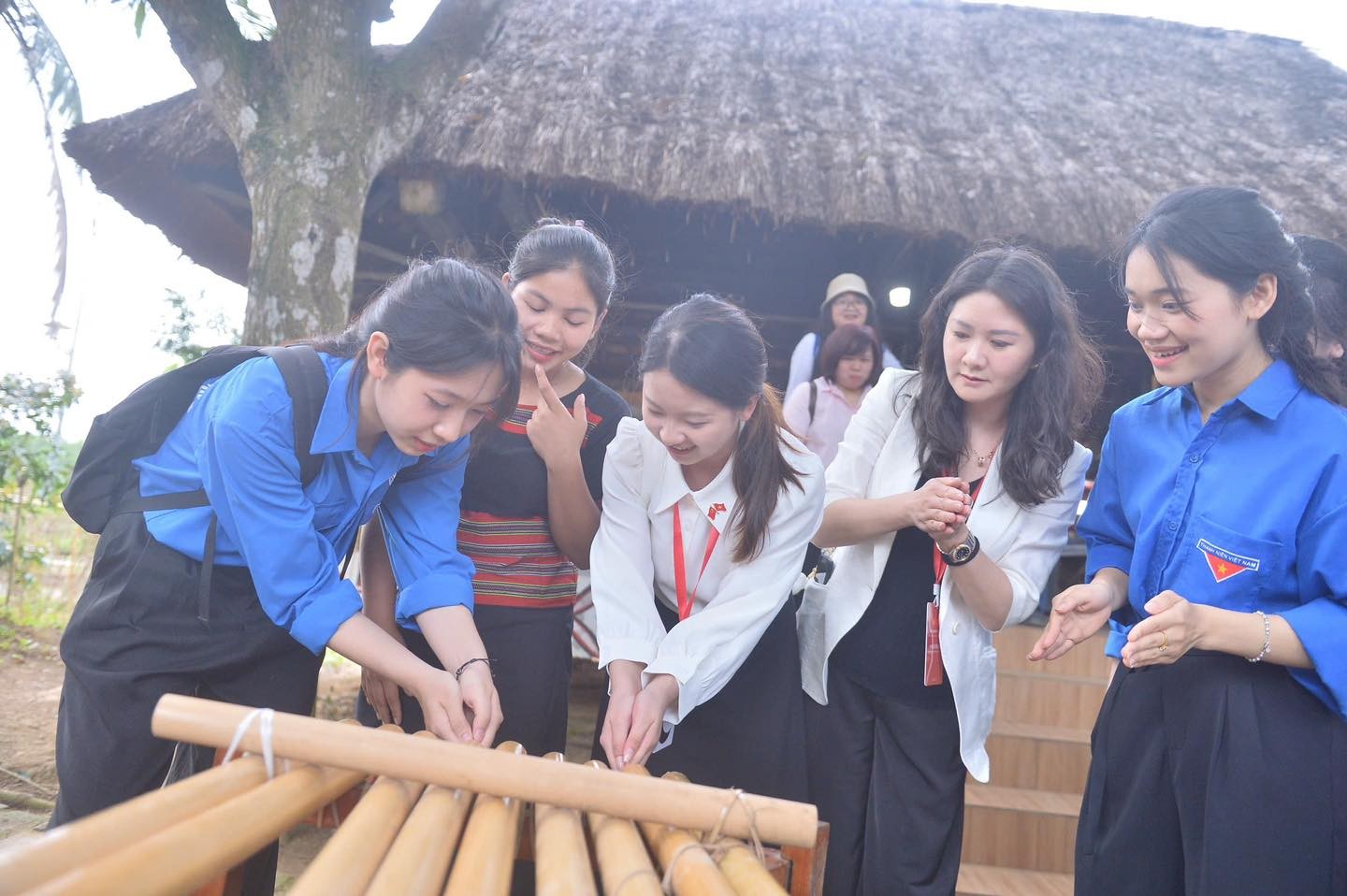 Đại biểu thanh niên Trung Quốc và tình nguyện viên Việt Nam cùng trải nghiệm đàn K'lông pút. Theo đó, đại biểu không chạm vào đàn, chỉ vỗ tay hoặc đập tay gần miệng ống, luồng không khí tạo ra sẽ kích thích âm thanh phát ra từ ống tre. (Ảnh: doanthanhnien.vn)