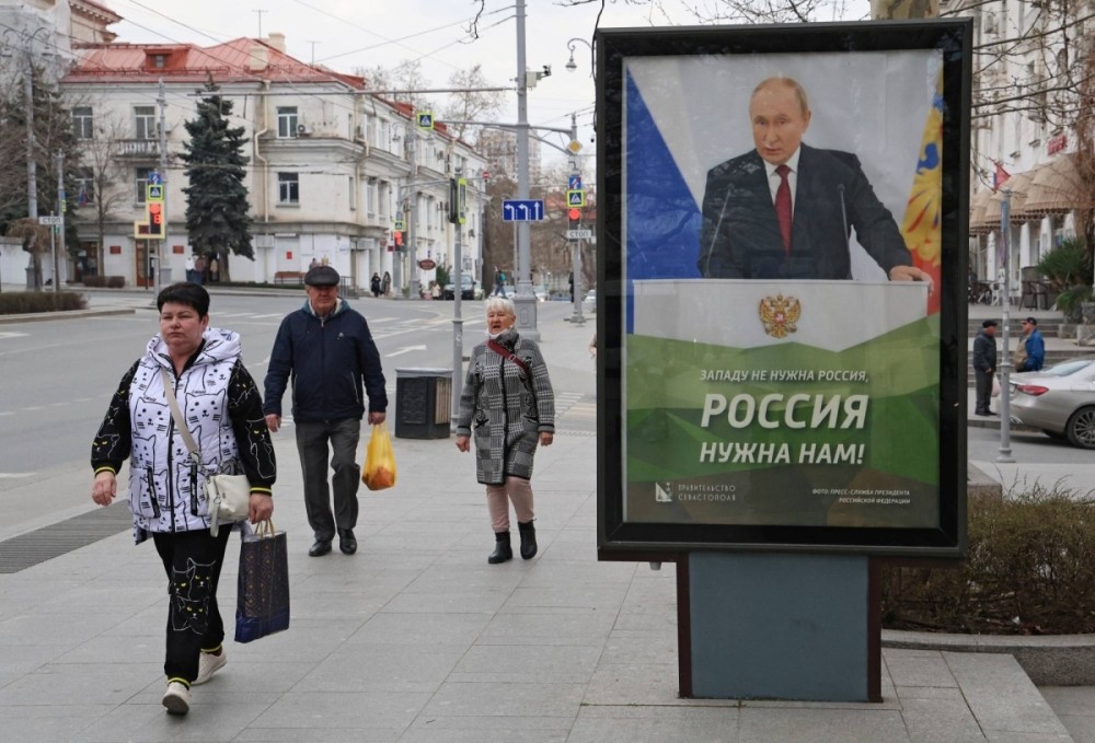 Người dân đi ngang qua biểu ngữ có hình Tổng thống Nga Vladimir Putin ở Sevastopol, Crimea, vào ngày 22/3/2025.