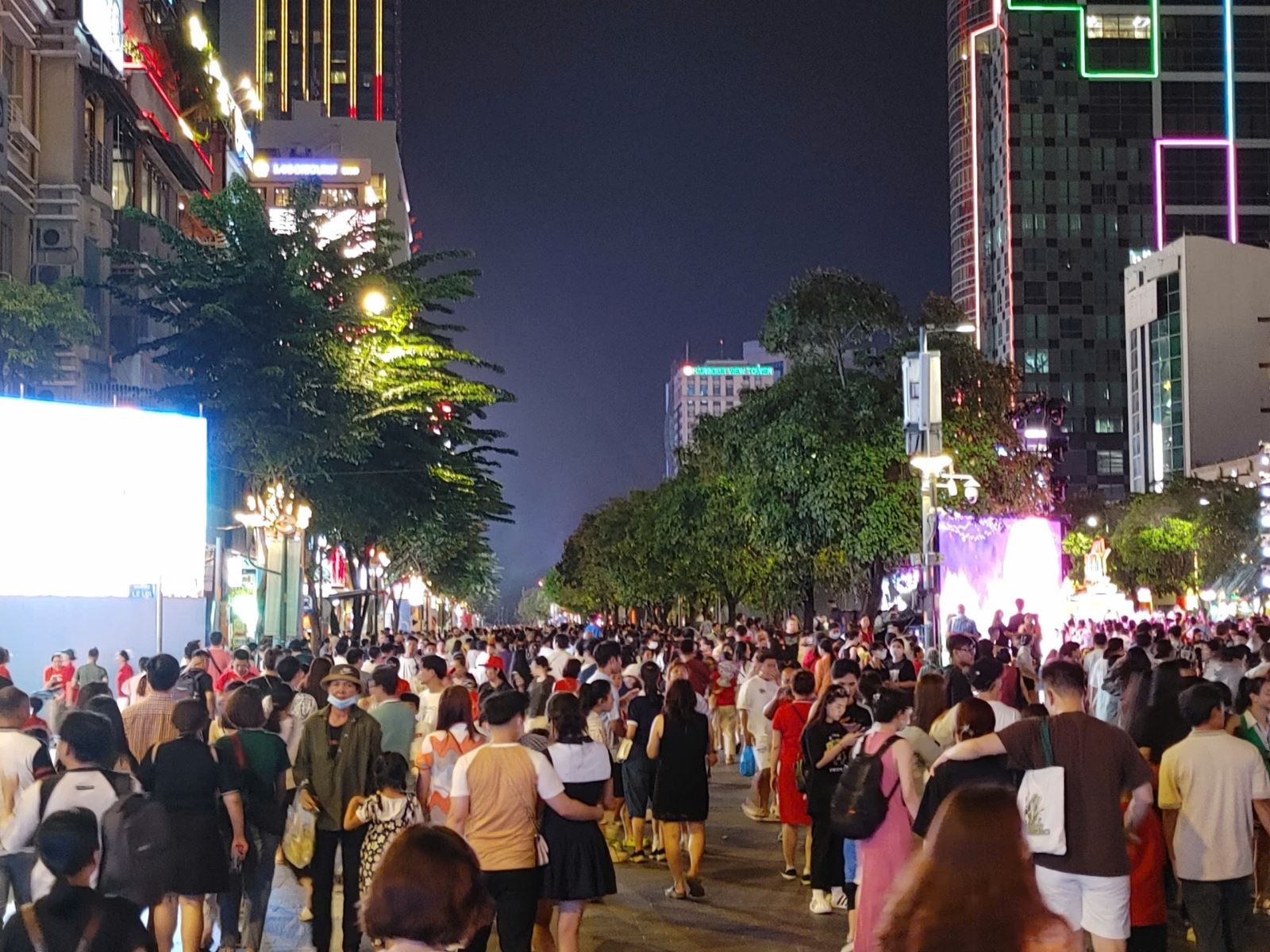 phố đi bộ Nguyễn Huệ đông nghịt người dân, du khách đổ về chờ xem bắn pháo hoa tại Công viên bờ sông Sài Gòn.