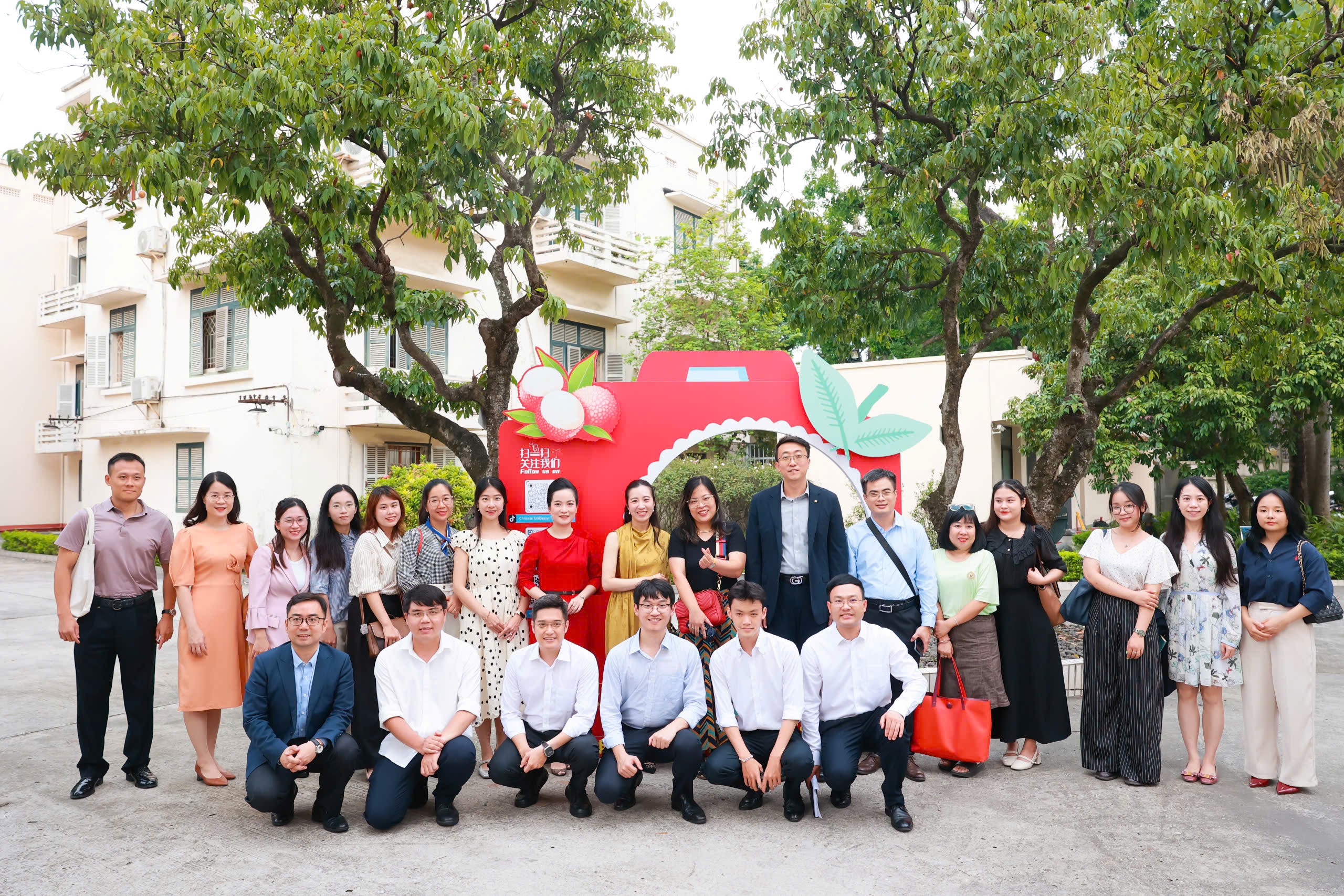 Cán bộ Đại sứ quán cùng phóng viên chụp ảnh lưu niệm trước cây vải lâu năm trong sân Đại sứ Quán.