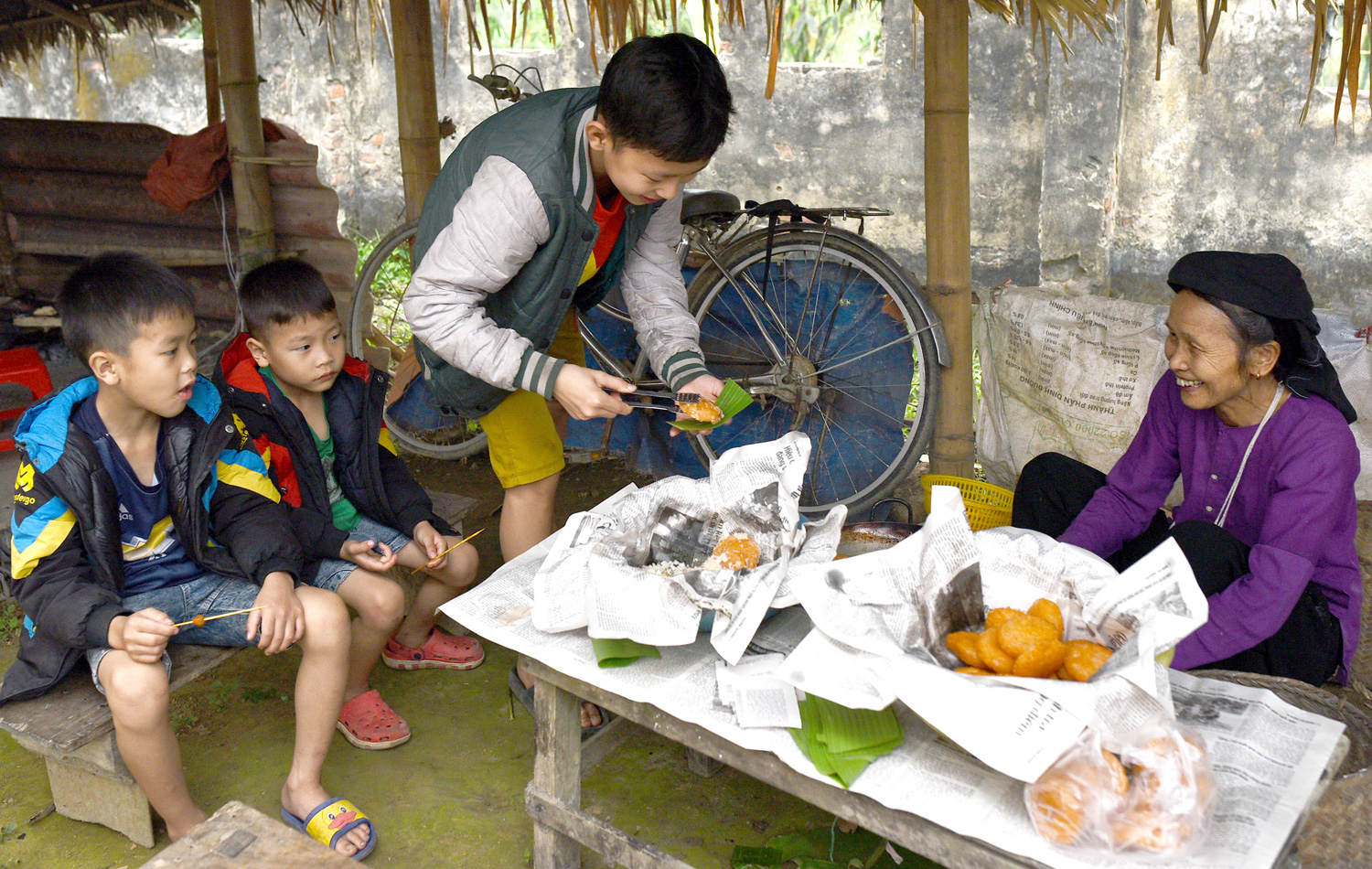 Một người phụ nữ Tày đang bán bánh rán cho những đứa trẻ.
