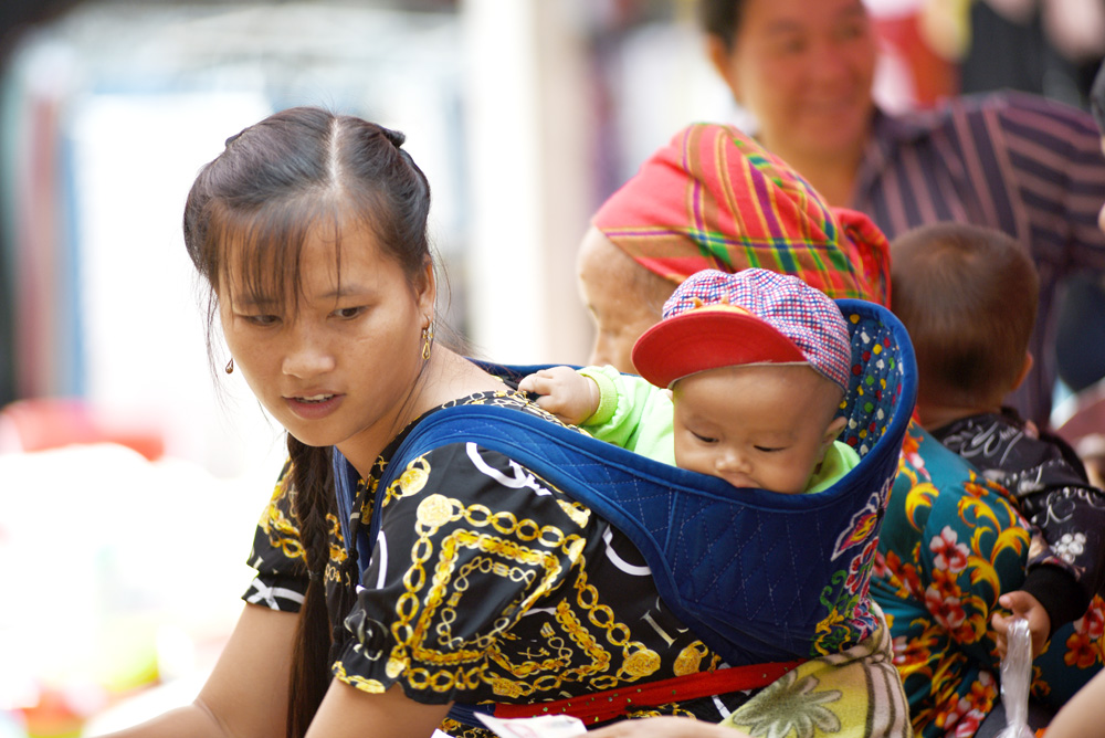 Các em bé cũng theo mẹ xuống chợ bằng những chiếc địu.