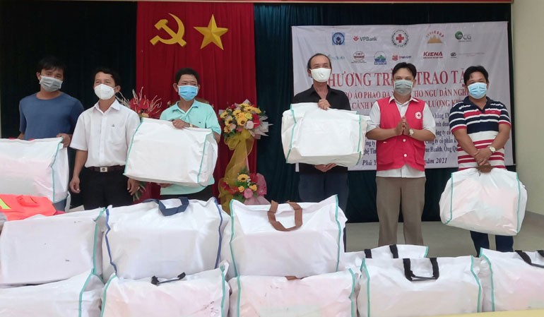 Phó Chủ tịch Hội Chữ thập đỏ tỉnh Nguyễn Hữu Sửu (thứ 2 từ phải sang) và đại diện lãnh đạo phường Phú Đông tặng bộ áo phao cứu sinh cho gia đình các ngư dân địa phương. Ảnh: NGỌC DUNG