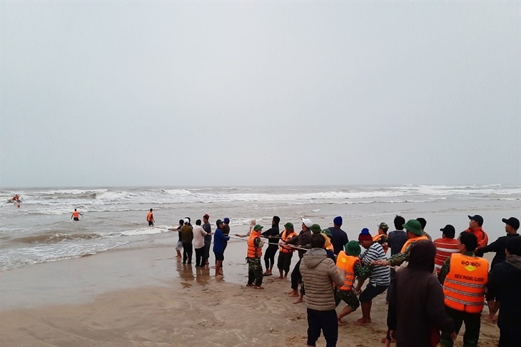 Cán bộ chến sỹ Đồn Biên phòng Lý Hòa phối hợp với chính quyền địa phương và người dân kéo được thuyền nan và ngư lưới cụ vào bờ. Ảnh: Hoài Nam