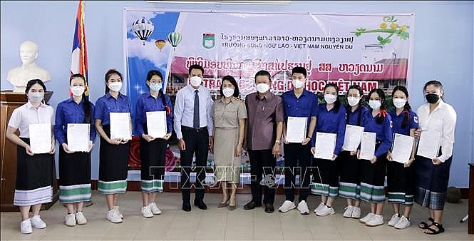 Ông Trần Đại Thắng, Bí thư thứ nhất Đại sứ quán Việt Nam tại Lào, chụp ảnh chung với các học sinh được nhận học bổng sau khi trao quyết định nhận học bổng của Trường Đại học Tôn Đức Thắng cho các em. Ảnh: Phạm Kiên/Phóng viên TTXVN tại Lào