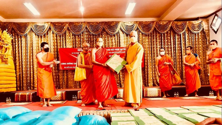 Thượng toạ Thích Minh Quang, Trụ trì chùa Phật Tích Vientiane (bên phải) trao tượng trưng thùng mỳ cho Hoà thượng Bounma Simaphome, Quyền Chủ tịch Liên minh Trung ương Giáo hội Phật giáo Lào.