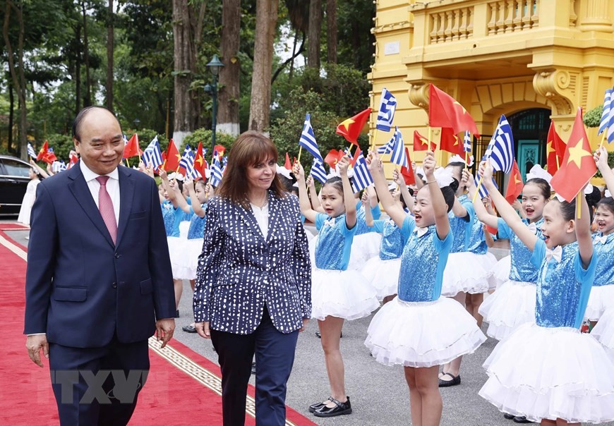 Chủ tịch nước Nguyễn Xuân Phúc và Tổng thống Hy Lạp Katerina Sakellaropoulou với thiếu nhi Hà Nội tại lễ đón. Ảnh: Thống Nhất/TTXVN