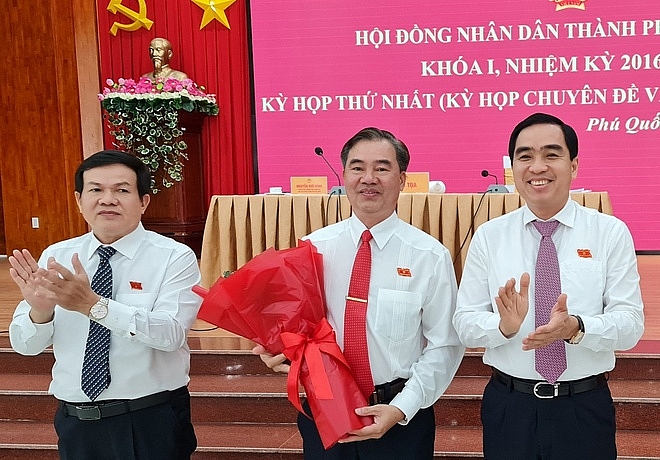 Chủ tịch HĐND TP. Phú Quốc Nguyễn Đức Kỉnh (trái) và Chủ tịch UBND TP. Phú Quốc Huỳnh Quang Hưng (phải) tặng hoa chúc mừng ông Đoàn Văn Tiến (Ảnh: Việt Tường/Zing)